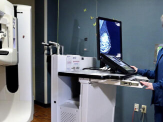 A lady technician standing in front of the scanning machine