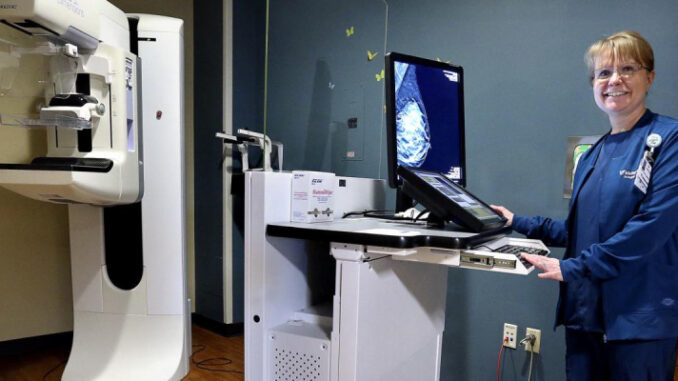 A lady technician standing in front of the scanning machine